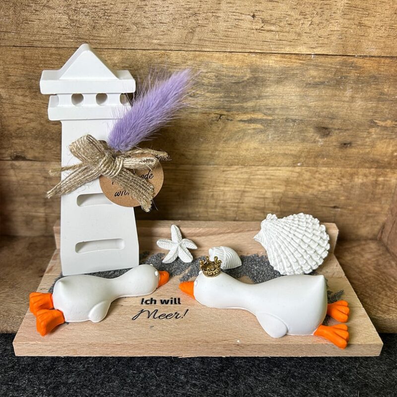 Handgefertigtes Entenpaar „Ich will Meer“ aus Gießkeramik mit Leuchtturm und Muscheldeko auf Holzplatte.