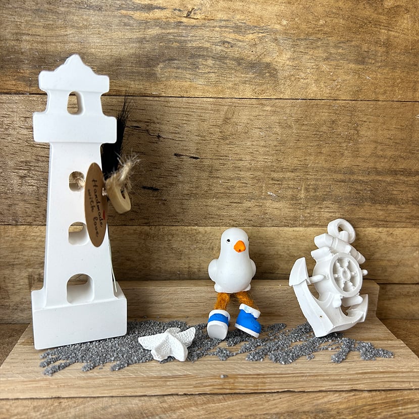 Maritimes Einzelstück: Kleine Möwe mit Leuchtturm aus handgefertigter Gießkeramik auf Holzplatte.