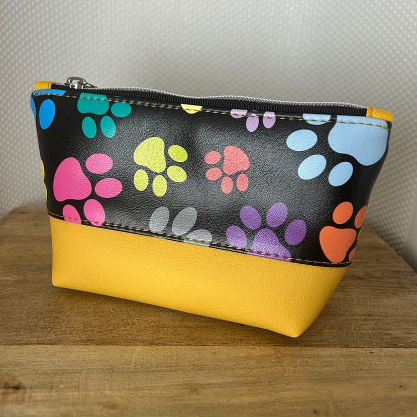 Handgemachtes Kosmetiktäschchen mit buntem Pfötchen-Print auf schwarzem Stoff und gelbem Kunstleder