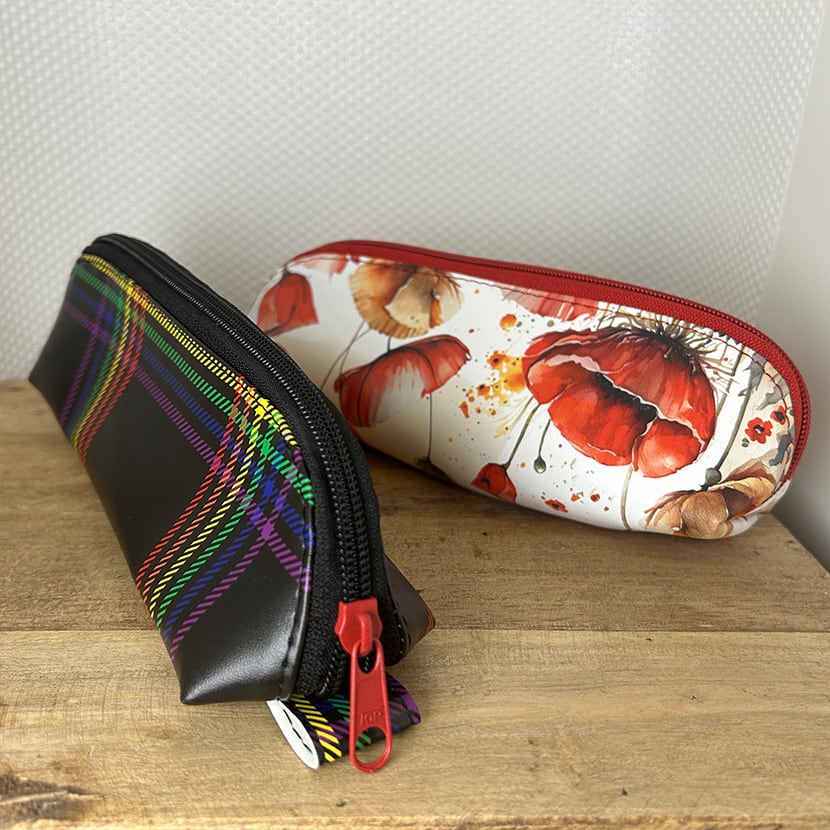 Zwei handgemachte lange Mäppchen – eines mit Mohnblumen-Design, eines mit schwarzem Regenbogen-Karo-Muster