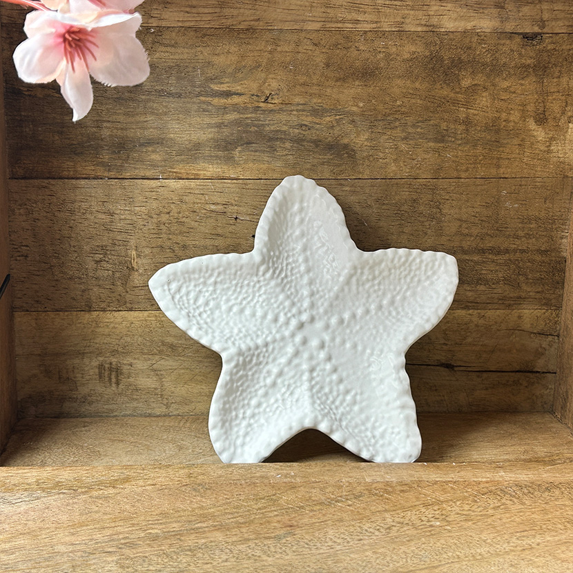 Weiße Seifenschale in Seestern-Form aus handgefertigter Gießkeramik auf Holzuntergrund