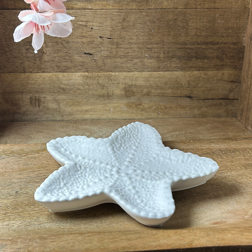 Weiße Seifenschale in Seestern-Form aus handgefertigter Gießkeramik auf Holzuntergrund
