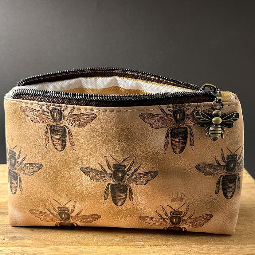 Handgenähte Mini-Kosmetiktasche aus goldbraunem Kunstleder mit dunklem Bienenmotiv und Zipper in Bienenform