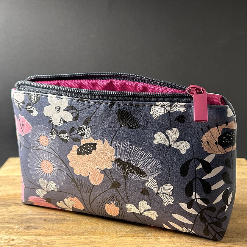 Handgenähte Mini-Kosmetiktasche mit floralen Motiven auf dunkelblauem Kunstleder und pinkem Innenfutter