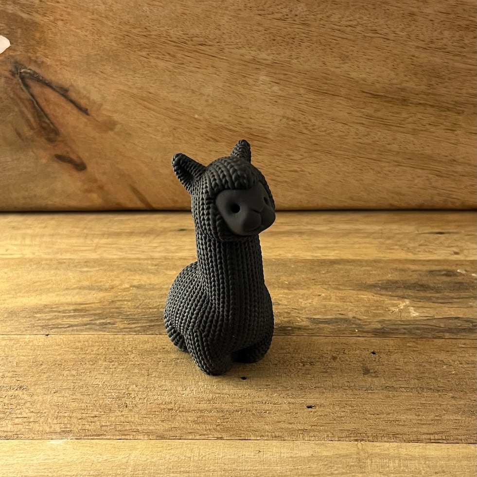 Schwarze Alpaka-Figur mit geriffelter Struktur in Einzelansicht.